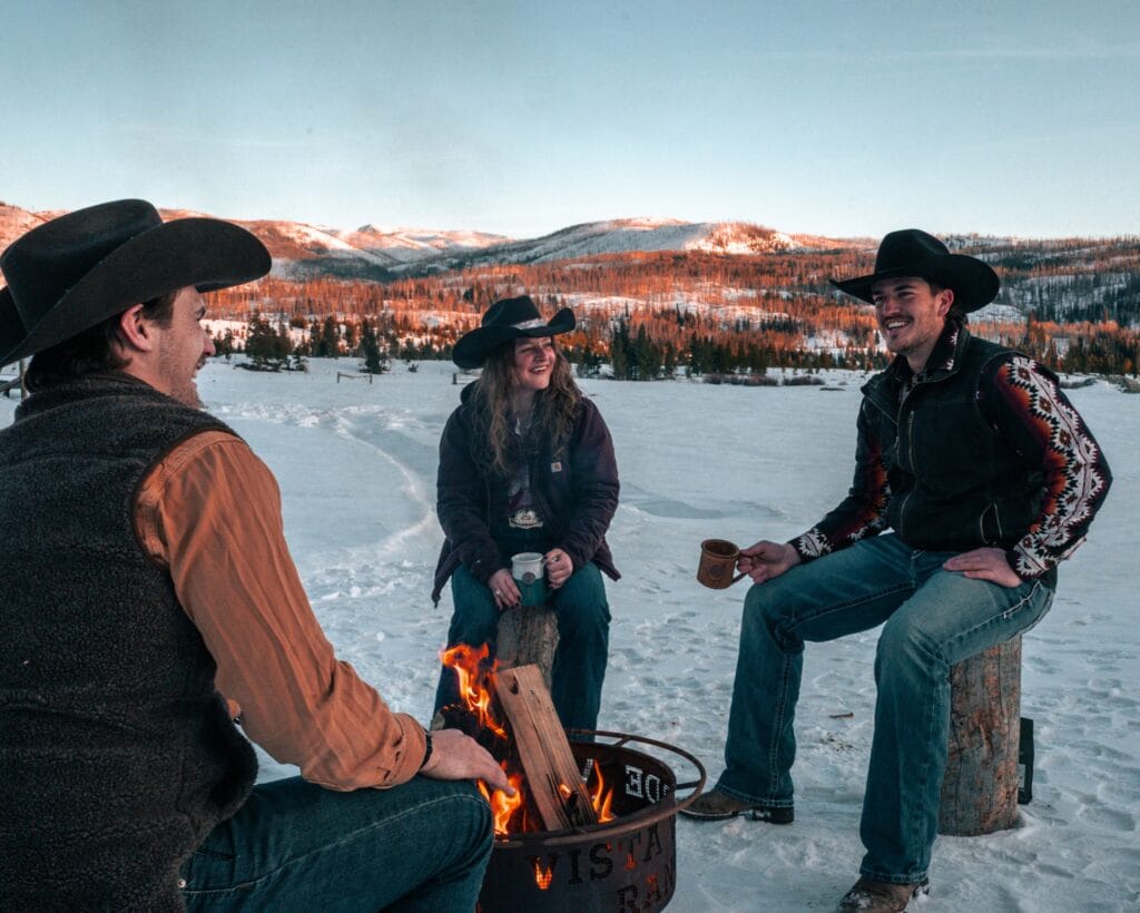 group of cowboys sitting around a campfire with coffee