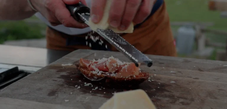 Pan Con Tomate Recipe Parmesan cheese being grated on Pan Con Tomate